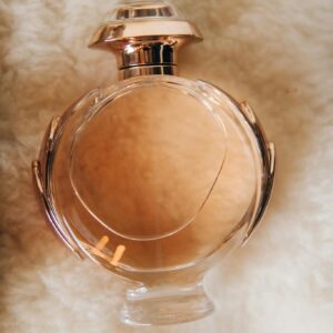 Close-up of a glass perfume bottle resting on a soft blanket surface, showcasing elegance and luxury.