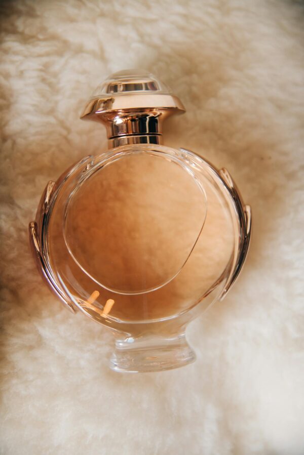 Close-up of a glass perfume bottle resting on a soft blanket surface, showcasing elegance and luxury.